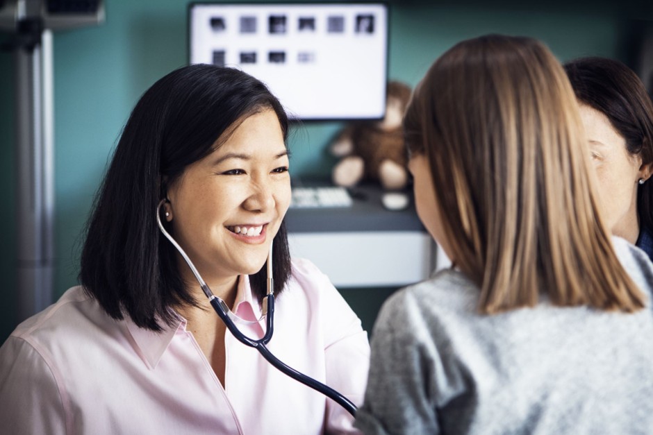 A doctor talking with a young patient and their parent during a consultation