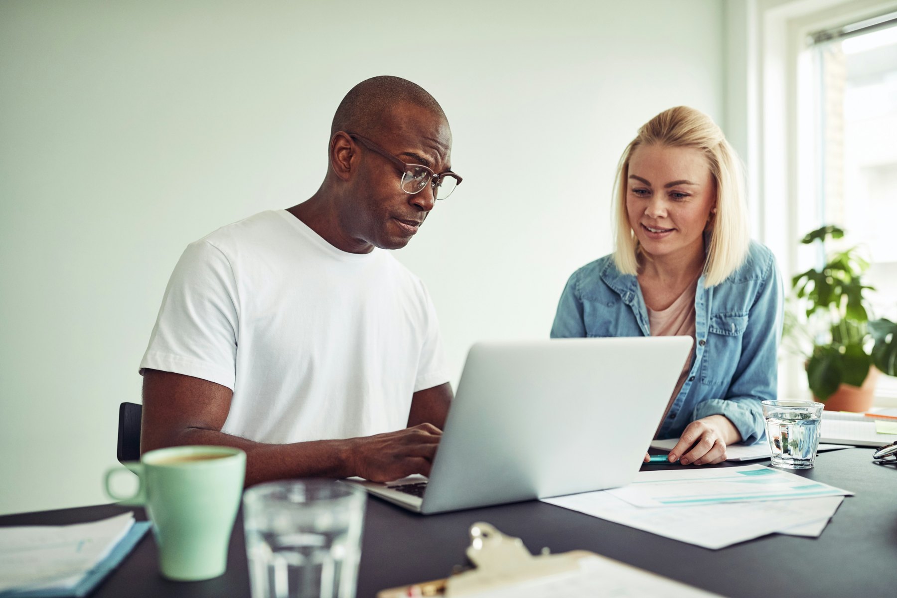 Two advisers reviewing a client's plan together on a laptop in a bright office