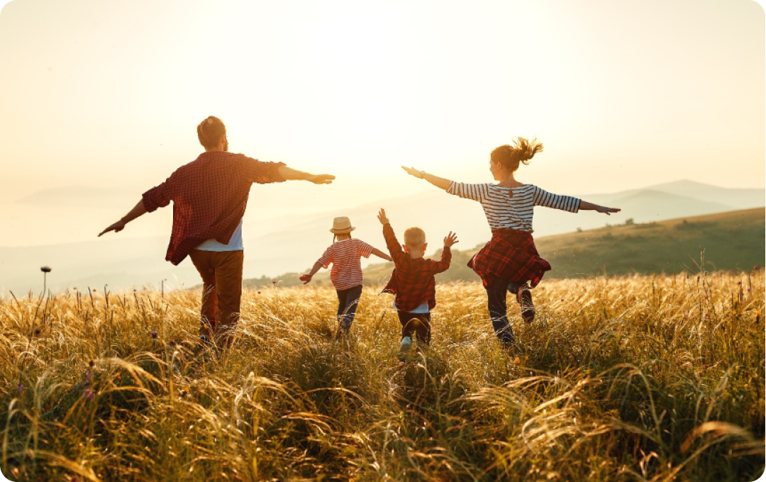 Family skipping through sun-lit meadows