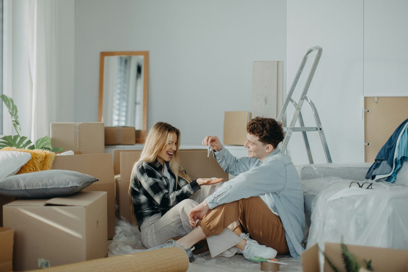 A couple sitting among moving boxes in a half-packed room, talking