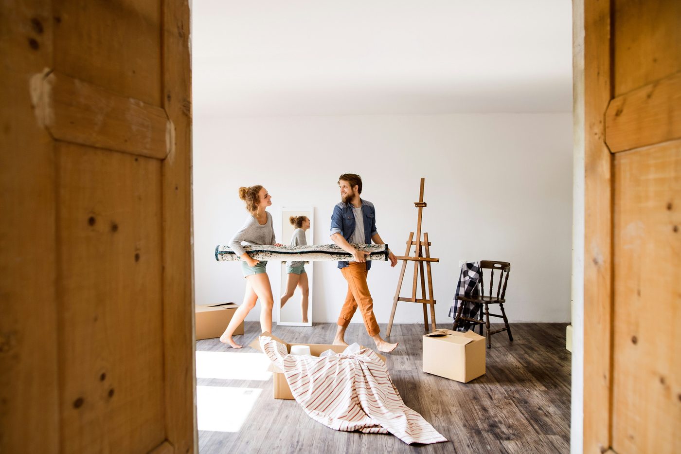 Two people moving a table in a bright, sparsely furnished room