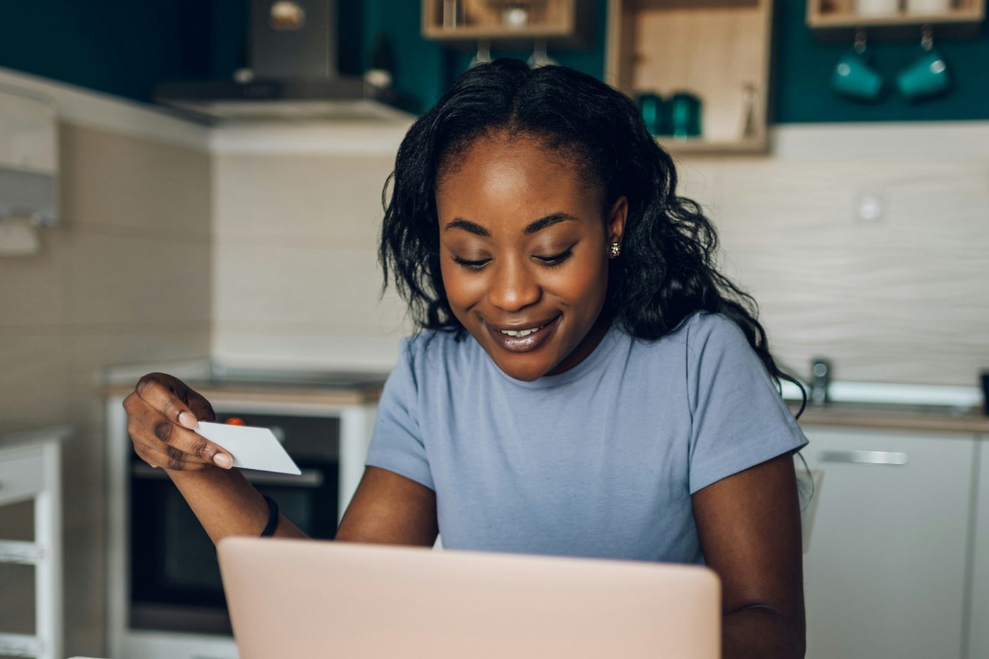 A woman comparing prices on a laptop while holding a bank card