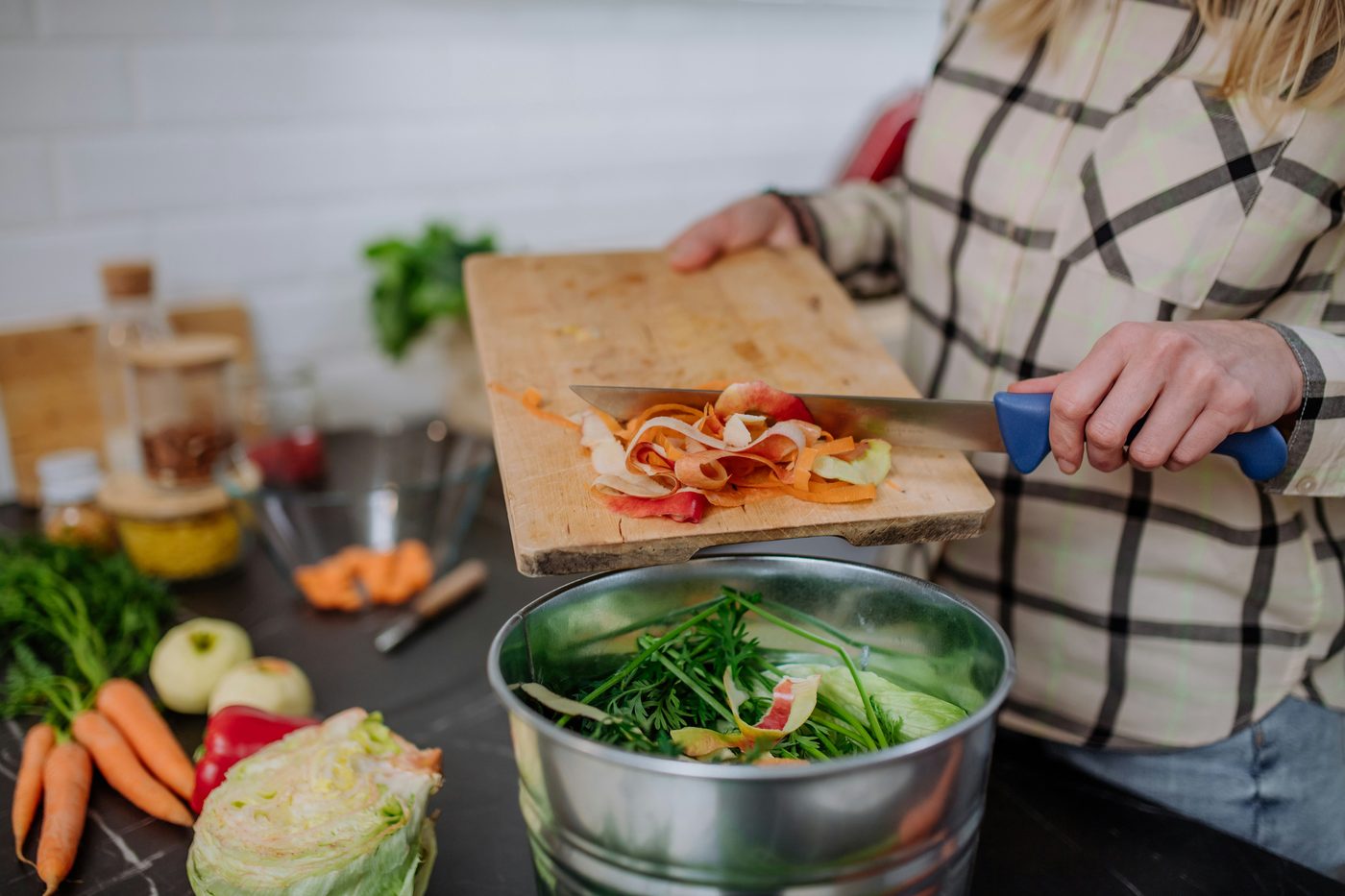 Vegetables being chopped on a board beside a bowl of greens