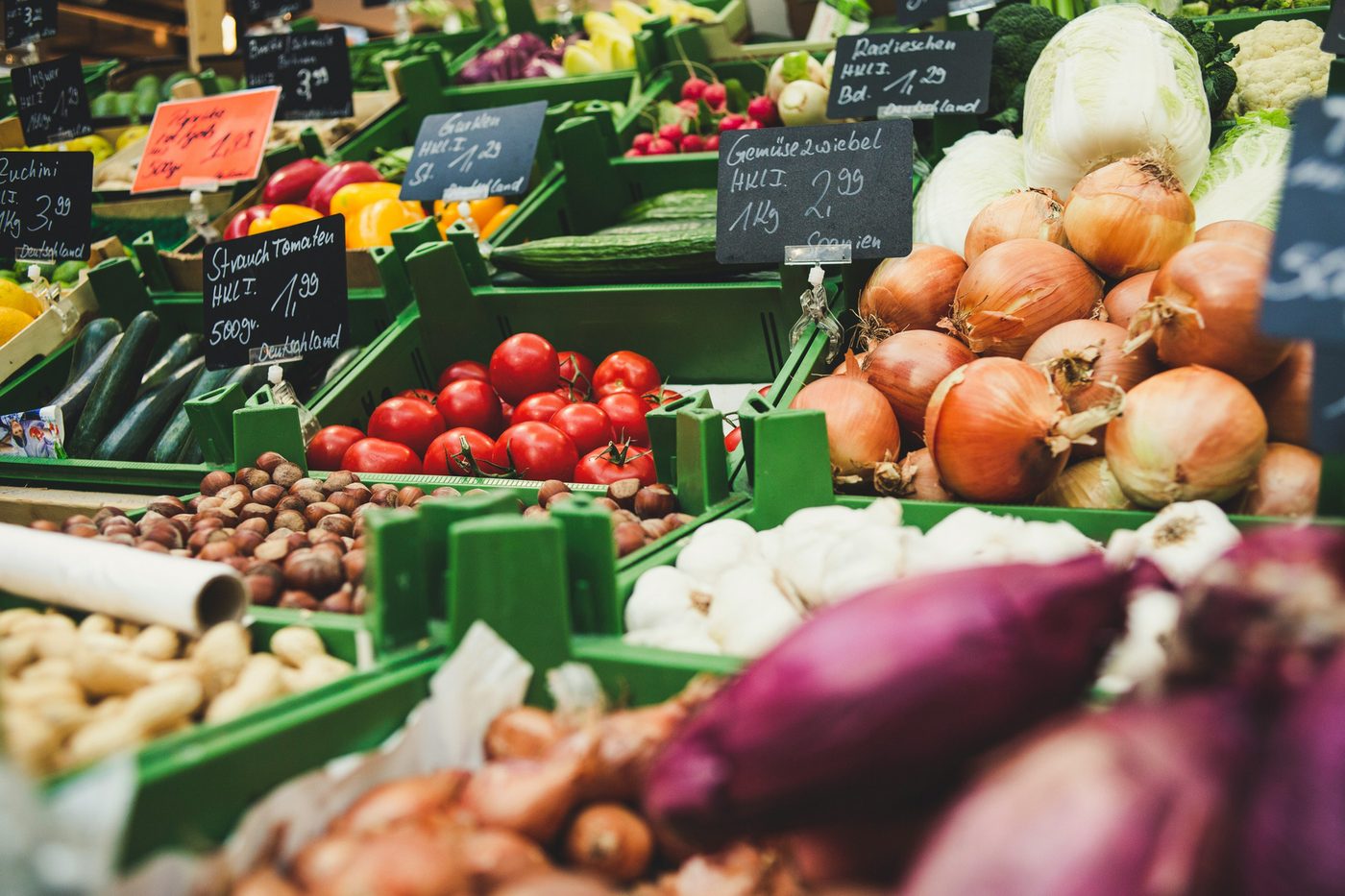 A market stall stacked with seasonal fruit and vegetables and chalk price signs