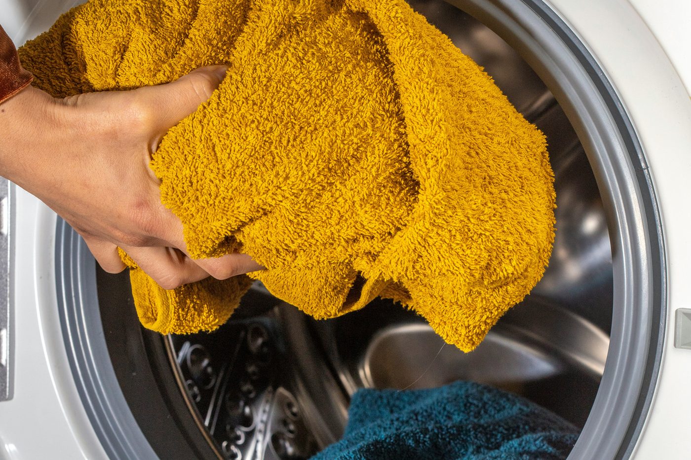 A towel being loaded into a front-loading washing machine